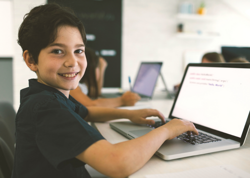 boy sitting at a computer trying code